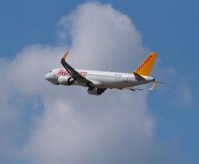 飞机模拟器外景追踪视角，空客A320在积云上方巡航，机身银白色在阳光下反光，背景蓝天深邃